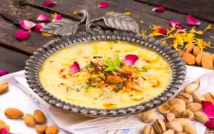 Image of a traditional Indian dessert, kheer, garnished with almonds, pistachios, and rose petals, served in an ornate silver bowl, as featured on the 'Kidney Bean Curry' page.